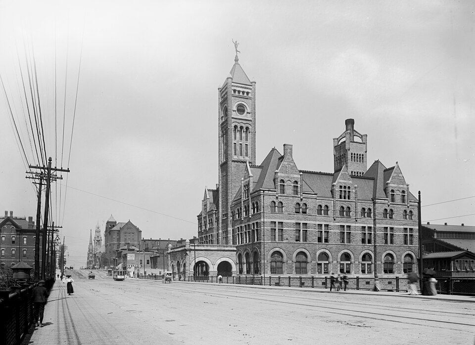 Union Station in Nashville around 1900: a stone train station with a tall clock tower beside a wide street with streetcars.
